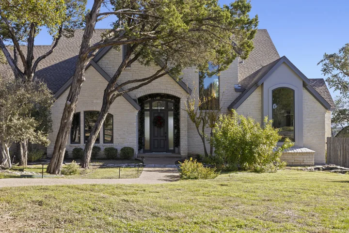 Stone-front Georgetown, Texas home with dark-framed windows and an arched entry